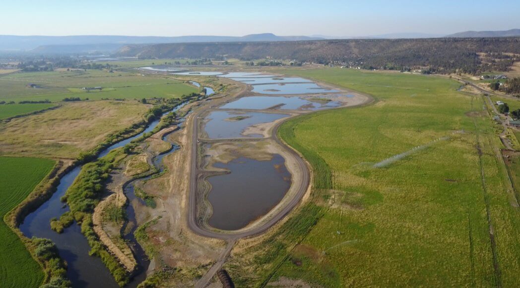Prineville wetlands project - built ponds of water spread out on the landscape next to the natural path of a river.