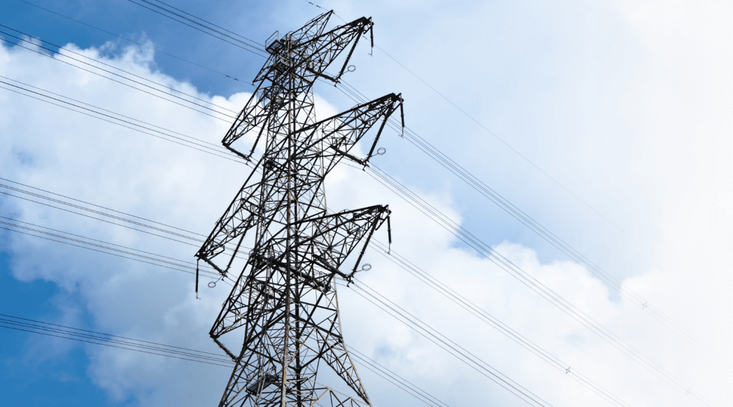 image of high voltage transmission lines in front of a pretty blue sky and fluffy clouds.