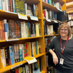 OEC Member, Lesley Atlansky, standing in the environmental studies book section that she curates at Powells bookstore.
